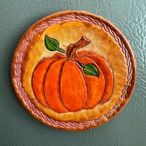 Handmade hand-carved pumpkin on leather with wooden backing and magnet